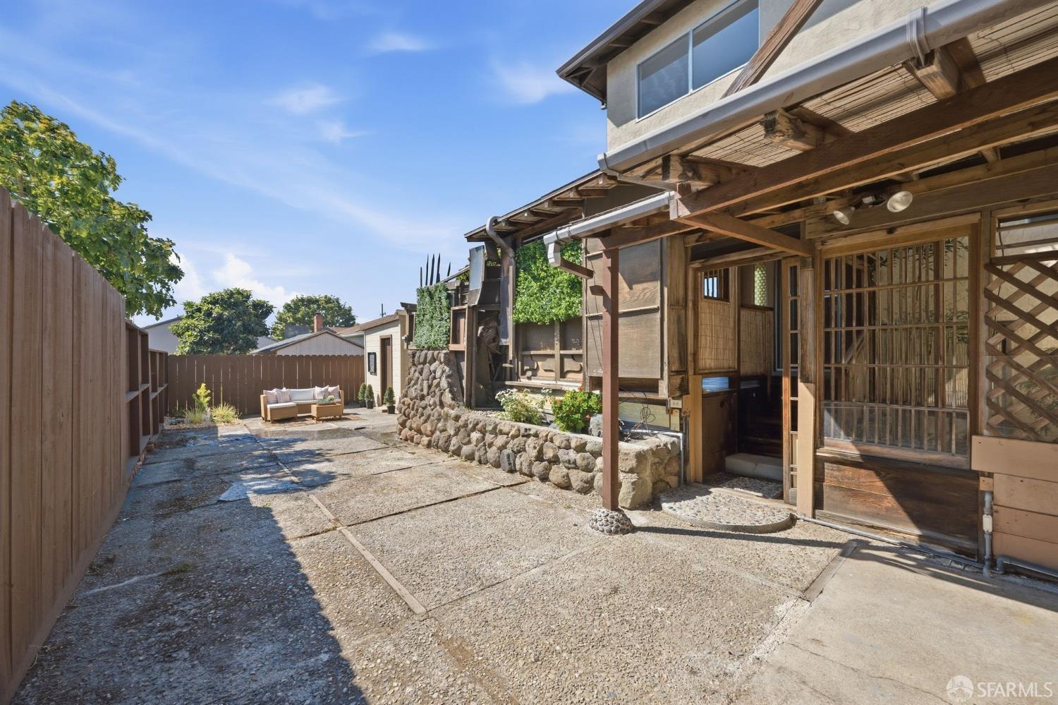 Backyard patio with a wood pergola, stone retaining wall, and outdoor seating.