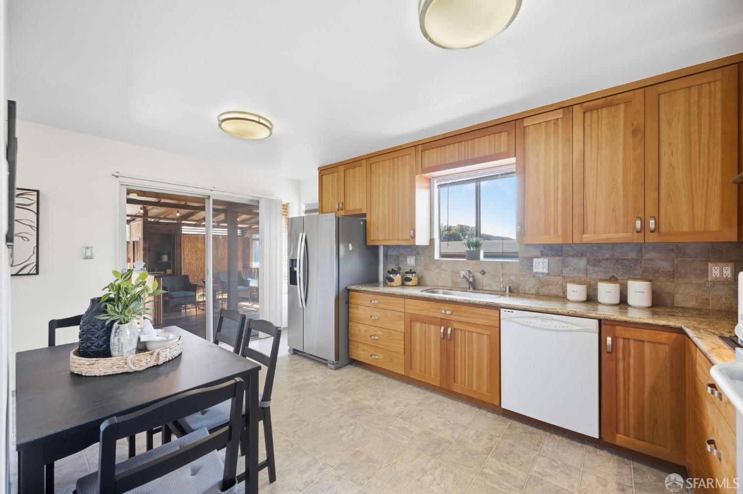 Kitchen with honey-colored cabinets, a dark dining table, and sliding doors to a covered patio.