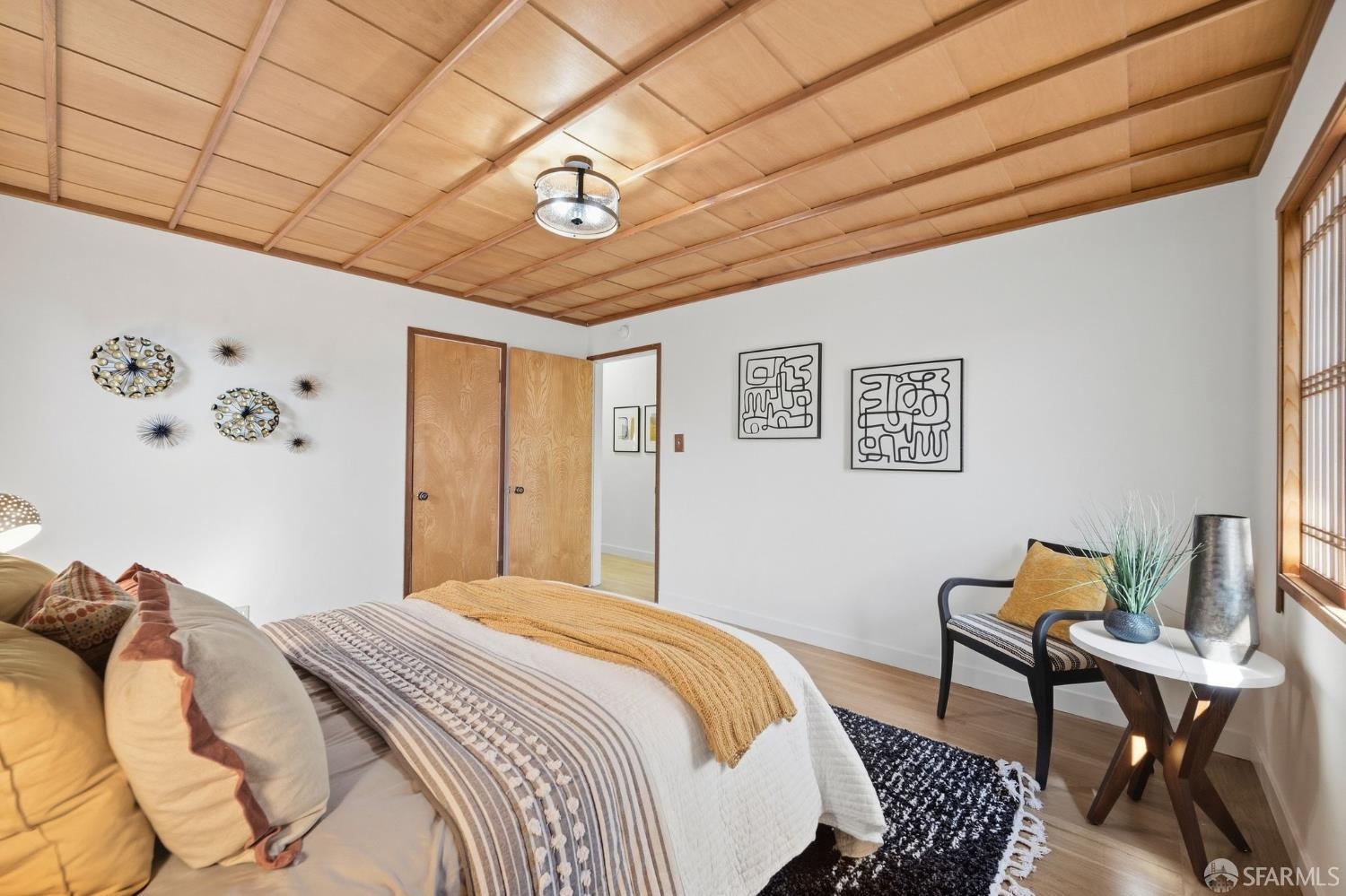 Bedroom with a striking wood-paneled ceiling and layered neutral bedding.