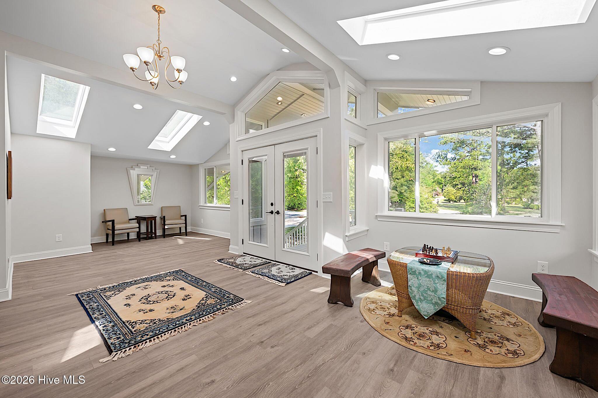 Furnished sunroom with large windows, skylights, and a wicker chess table.
