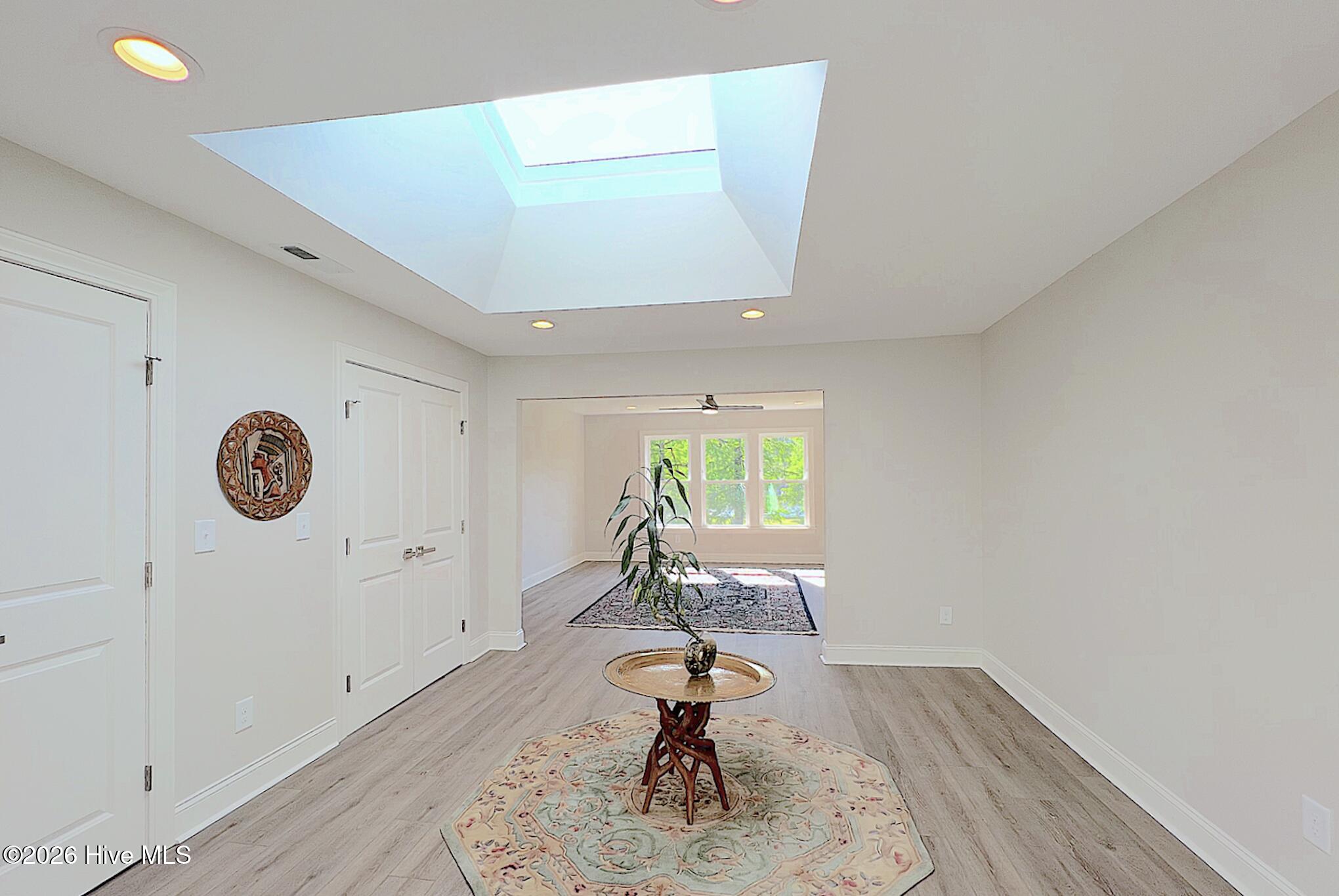 Entry hall with a large skylight and a decorative table on a patterned rug.