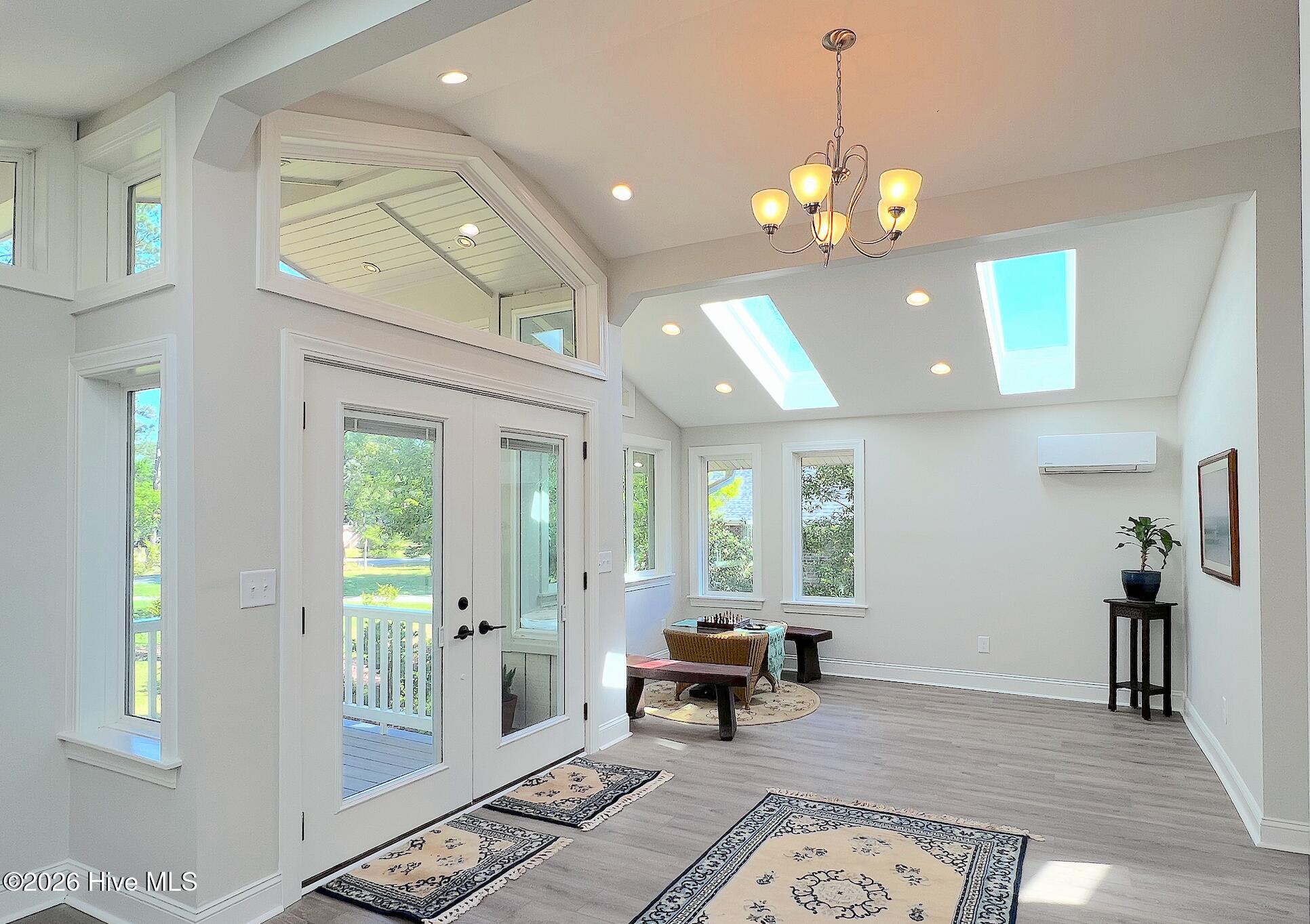 Bright room with skylights, tall windows, glazed porch doors, and a small chess table.