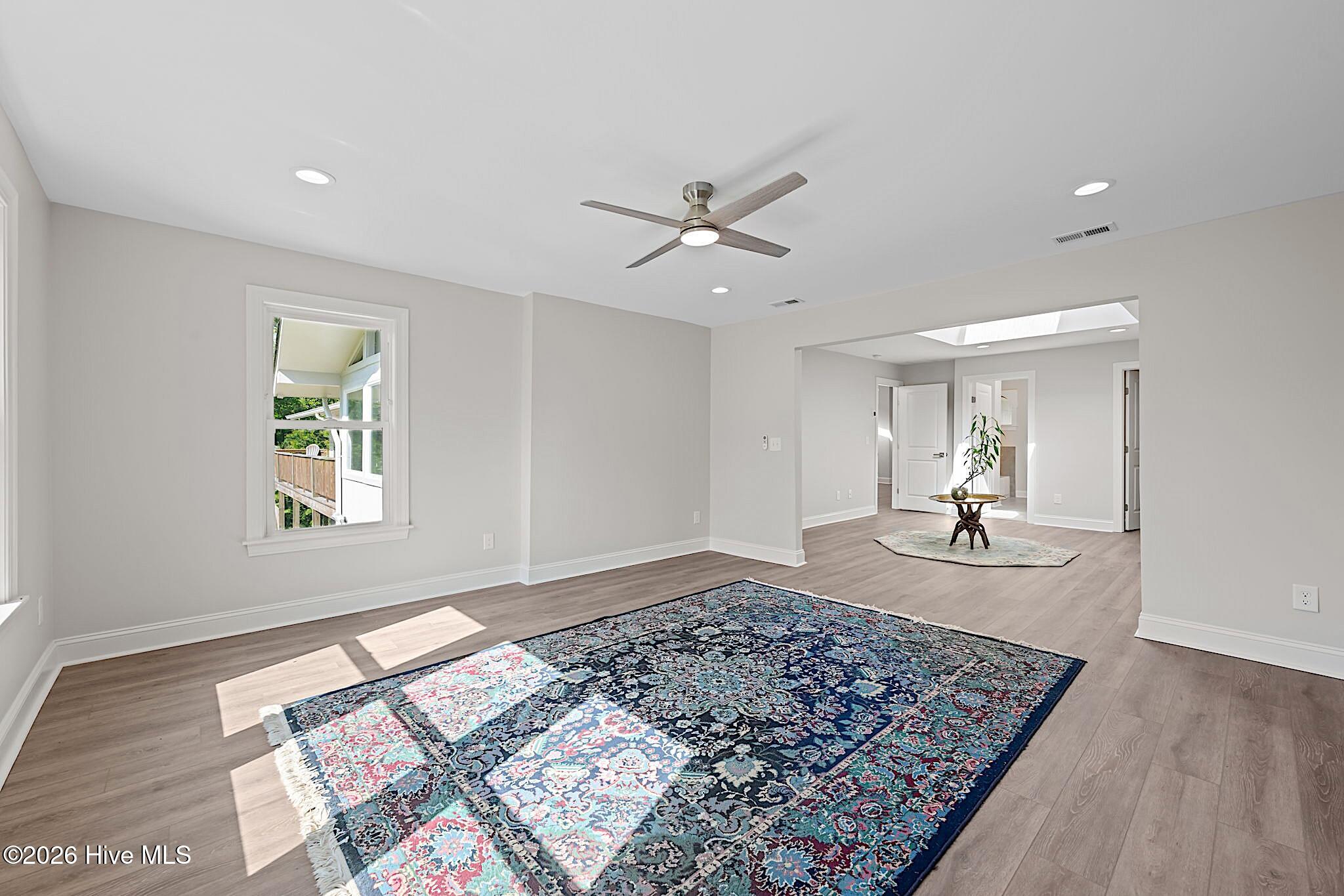 Open living room with a large blue patterned rug, ceiling fan, and view toward a deck.