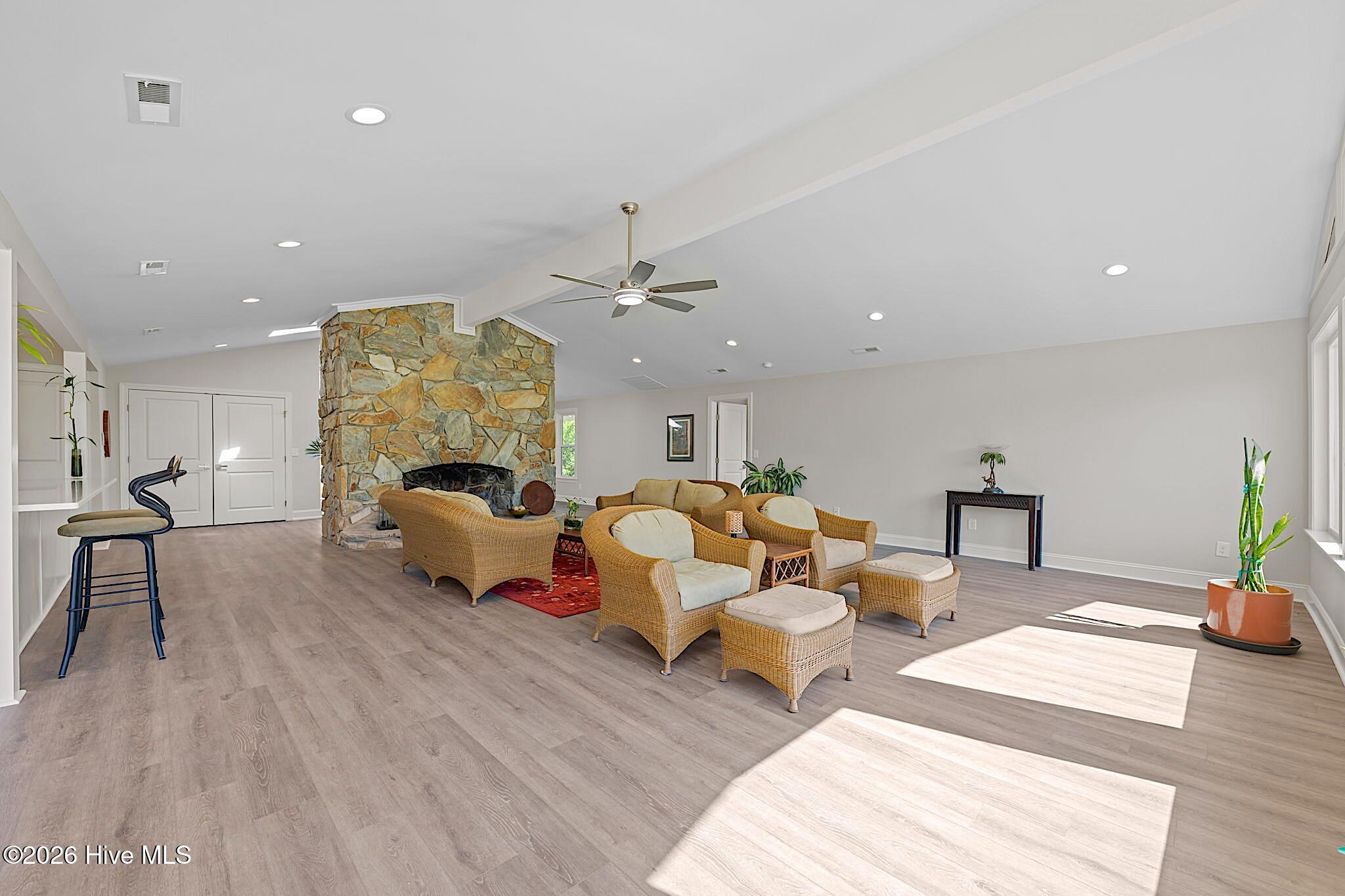Living room with a floor-to-ceiling stone fireplace and wicker seating in sunlight.