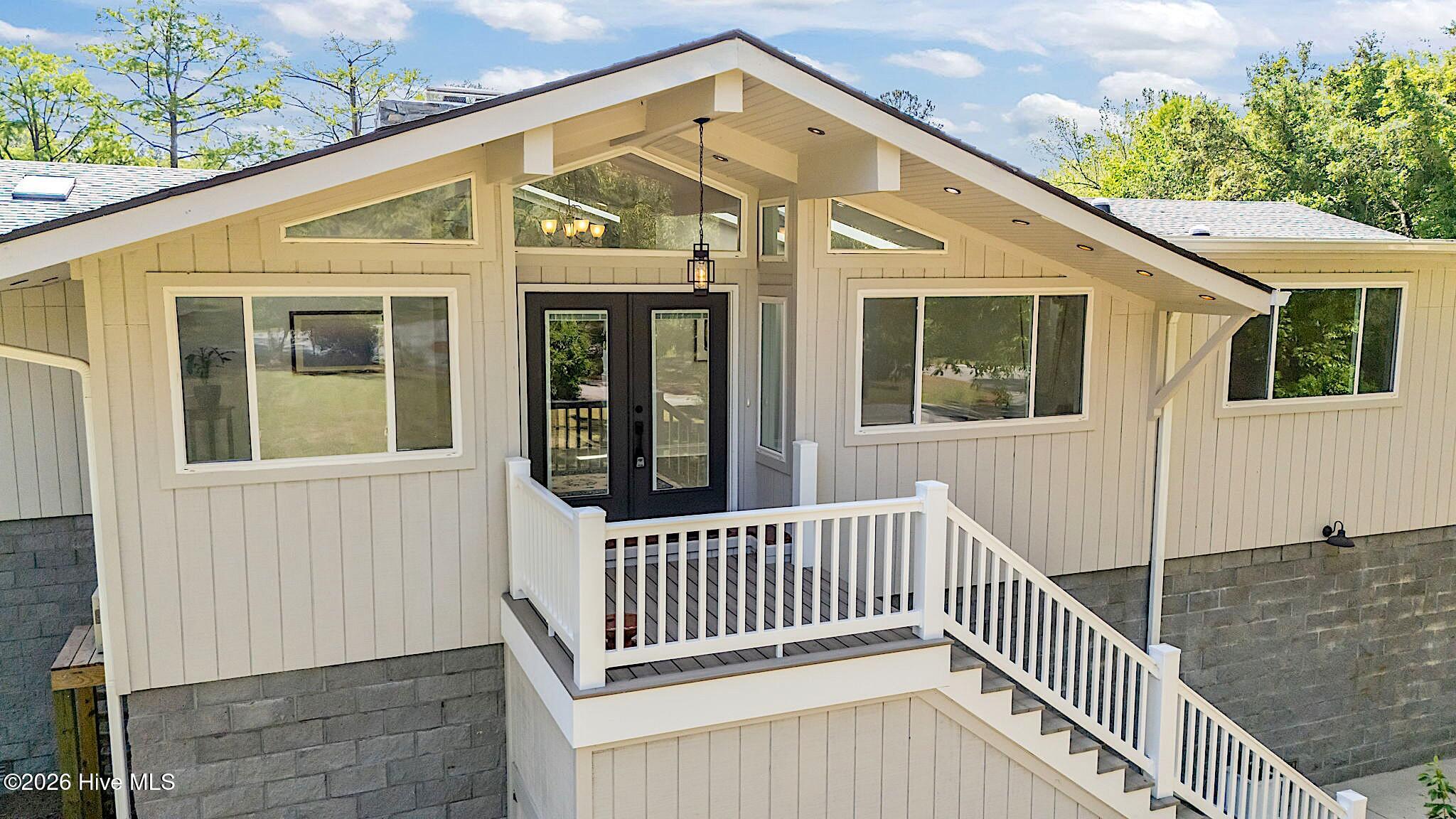 Home exterior with a peaked roof, raised porch, white railings, and long staircase.