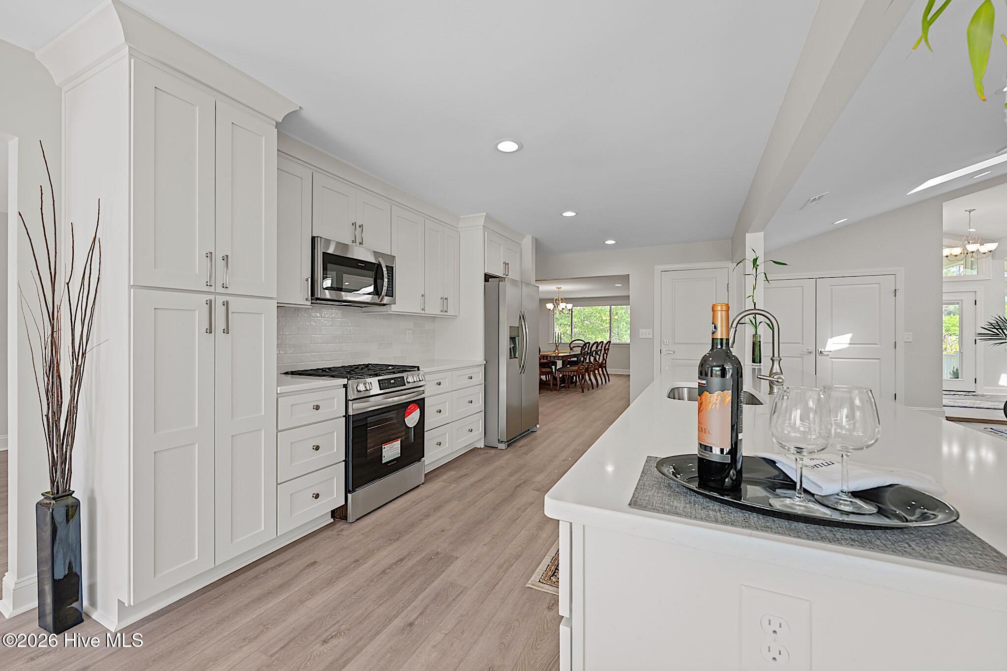 Bright kitchen with white cabinets, stainless steel appliances, and a long island with a sink.