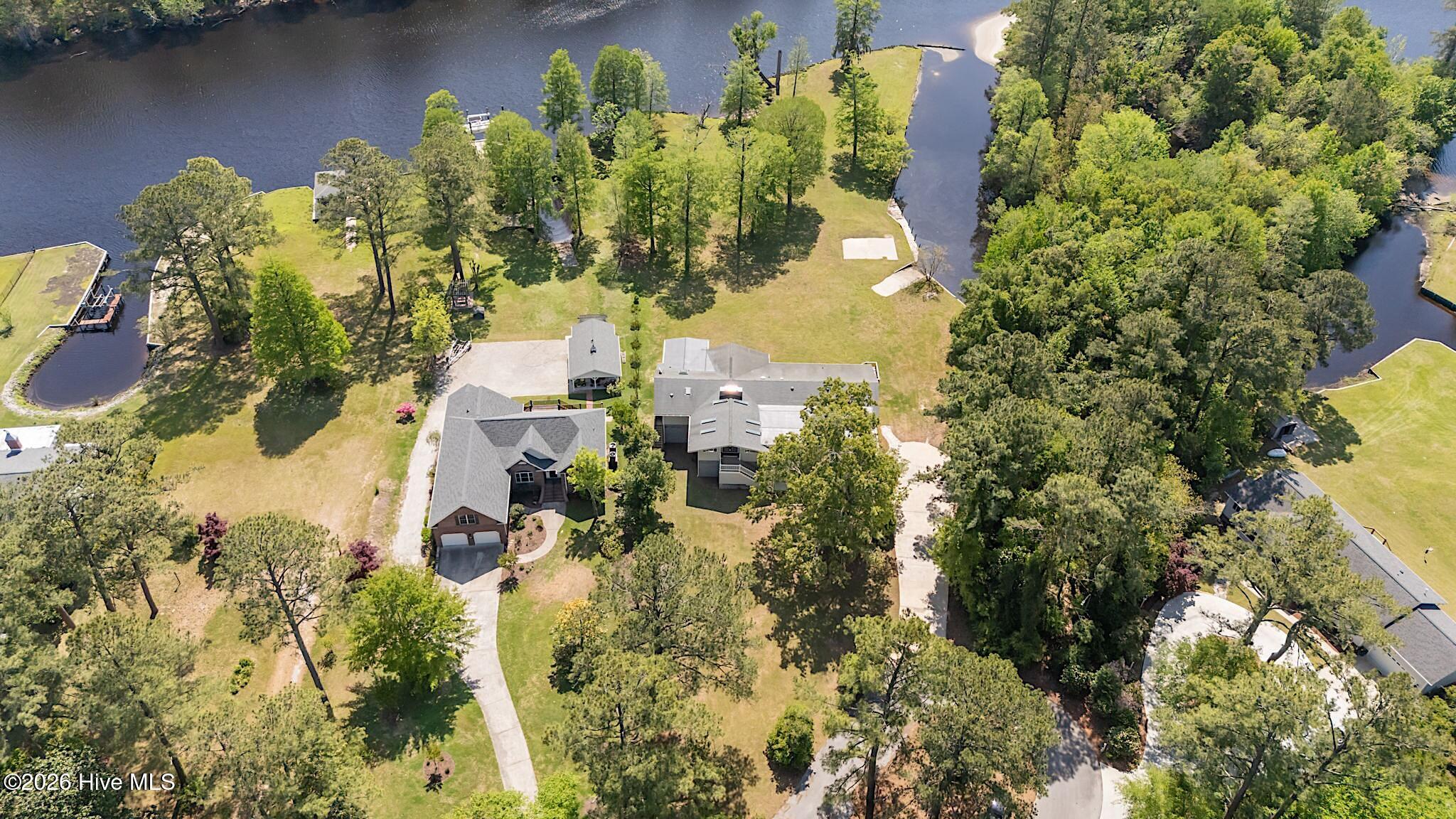 Aerial view of homes on landscaped waterfront grounds, surrounded by trees and waterways.