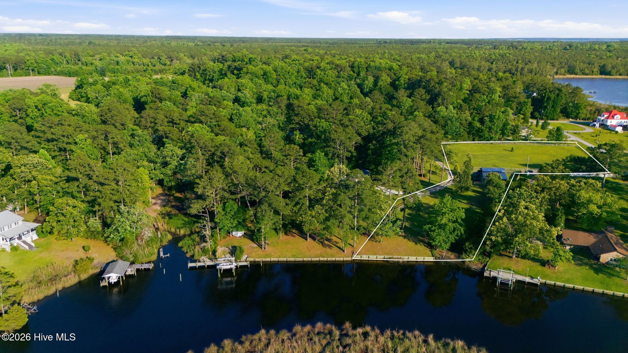 Aerial view of wooded waterfront lots outlined beside a broad creek.