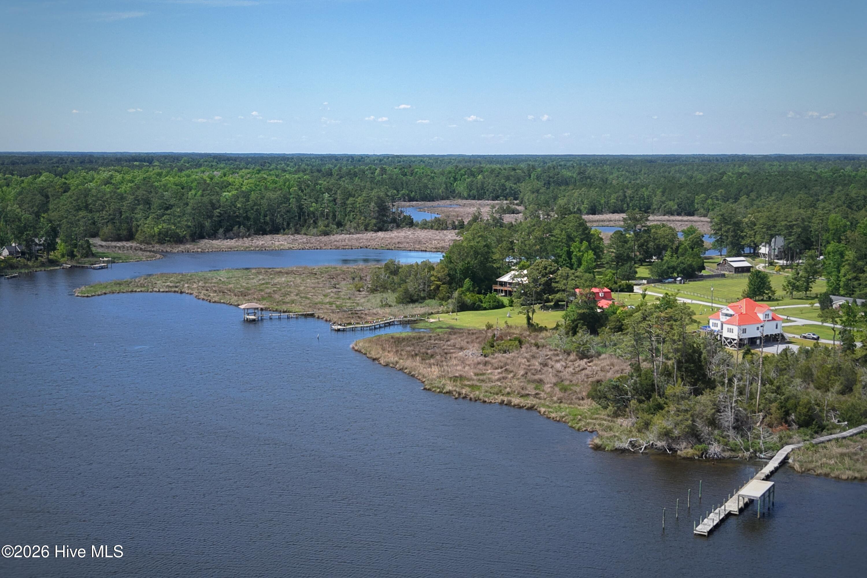 Aerial view of wooded waterfront lots, marsh shoreline, docks, and nearby homes.