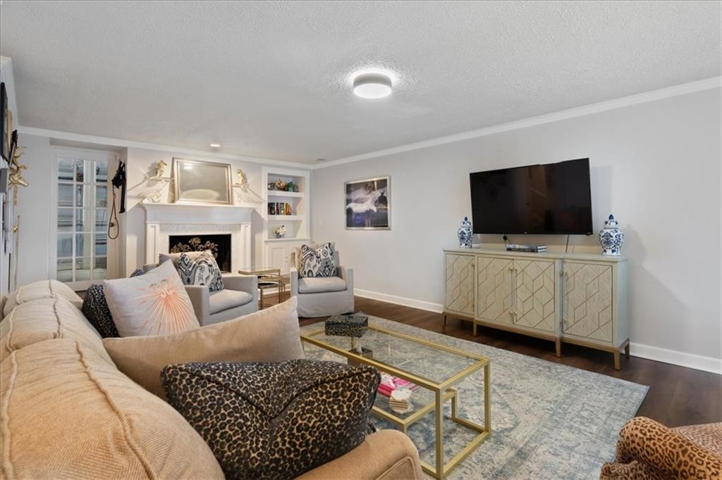 Living room with a white fireplace, built-in shelves, and television above a geometric-front cabinet.