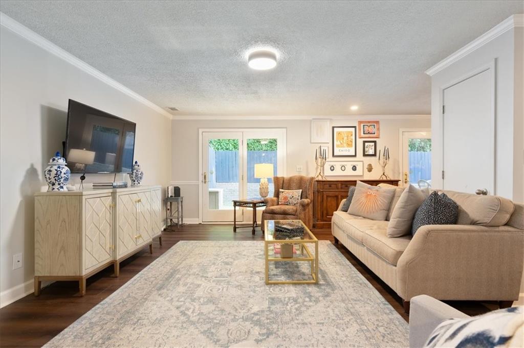 Furnished living room with a beige sectional, patterned rug, and glass doors to a fenced area.
