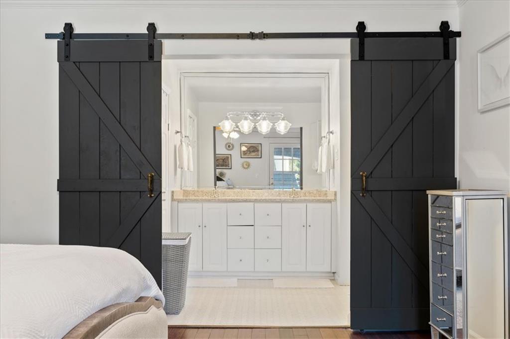 Bedroom with black barn doors opening onto a bright bathroom vanity.