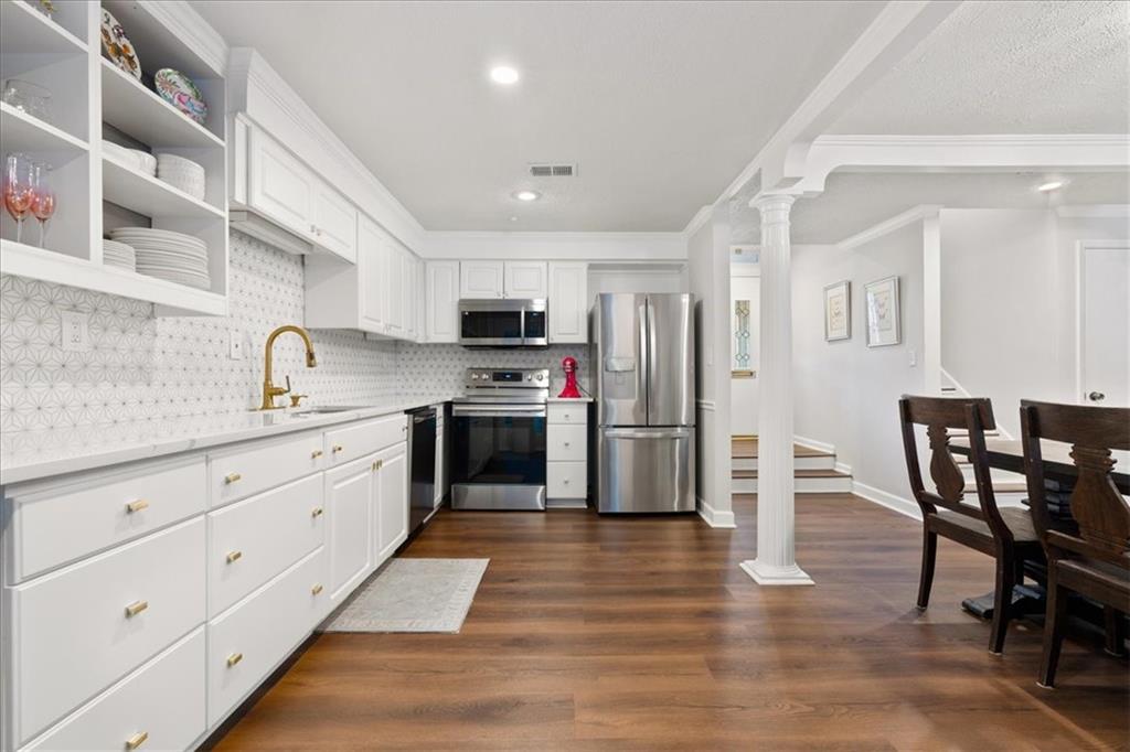 White kitchen with geometric tile backsplash, stainless steel appliances, and an adjoining dining area.