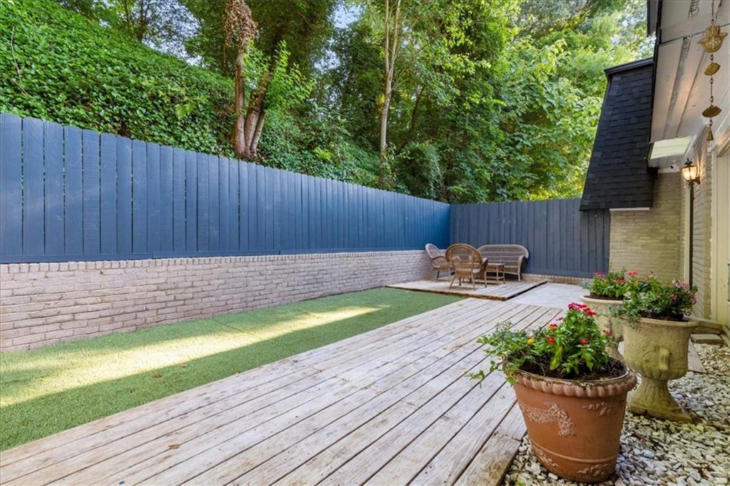 Fenced patio with a weathered wood deck, artificial turf, and a small outdoor seating area.
