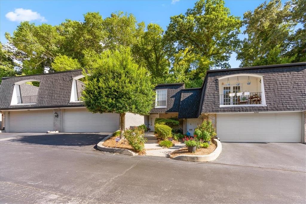 Residence with attached garages and a landscaped entrance beneath mature trees.