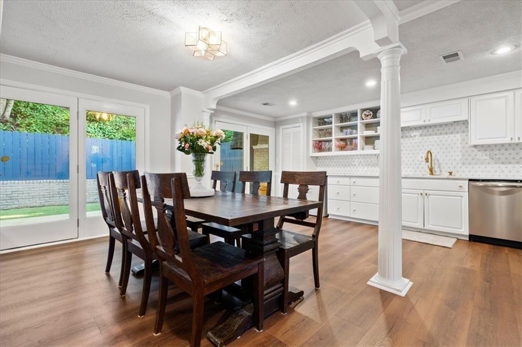 Dining room with a dark wood table, glass doors, and an adjoining white kitchen.