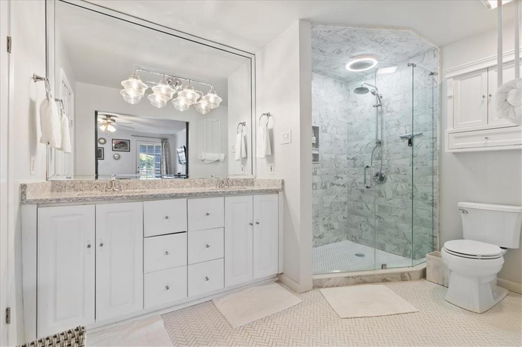 Bright bathroom with a long white vanity and a glass-enclosed marble shower.