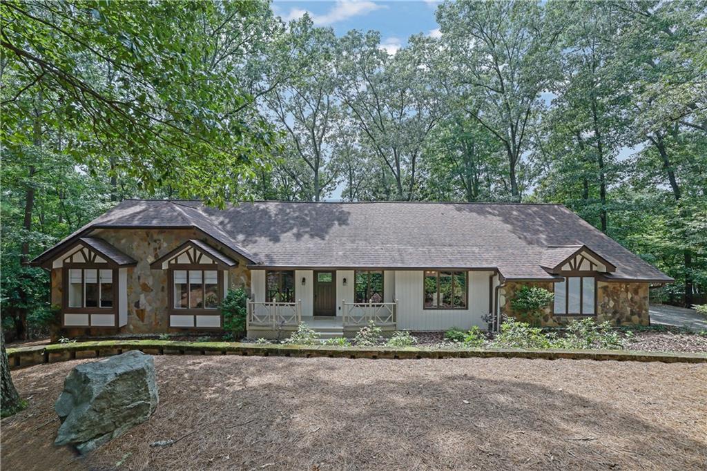 Ranch-style home with stone accents and a covered porch in a wooded setting.