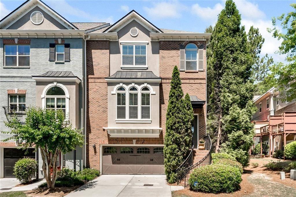 Brick townhouse with a double garage, arched windows, and a landscaped front walkway.