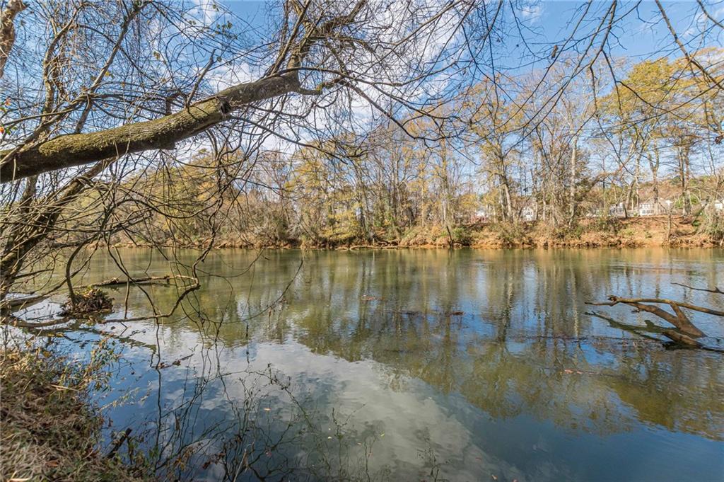 Calm water framed by bare trees, with homes visible on the far bank.
