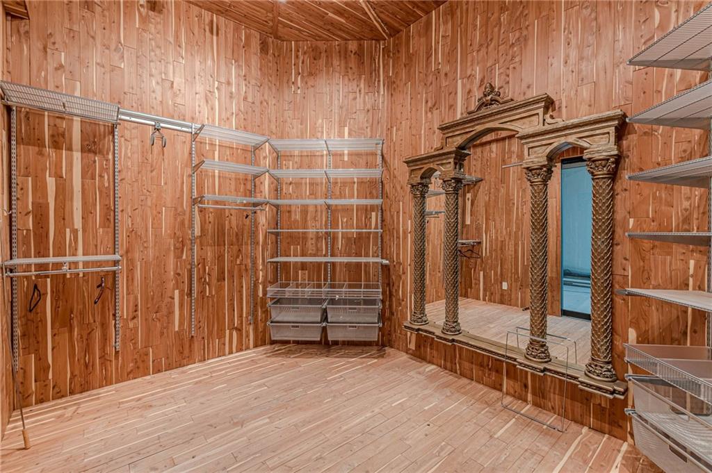 Wood-paneled walk-in closet with metal shelving and an ornate carved dressing area.