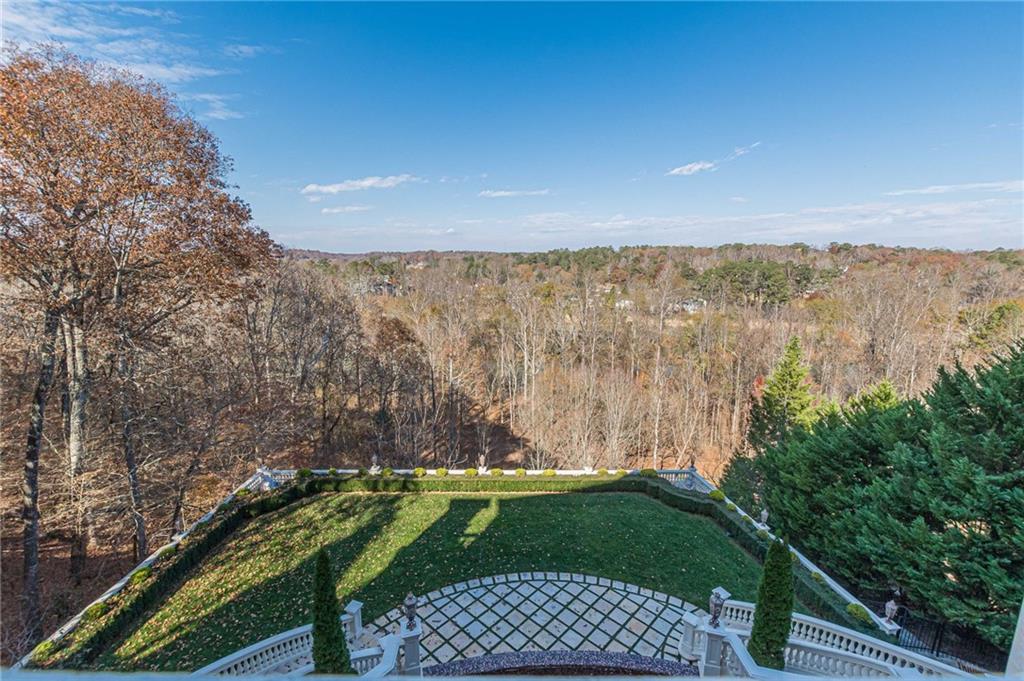 Wooded autumn view beyond a landscaped lawn and geometric stone patio.