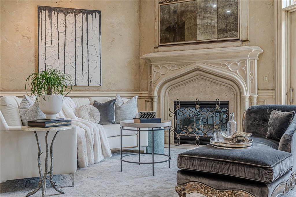 Living room with an ornate carved fireplace, white sofa, and dark chaise lounge.