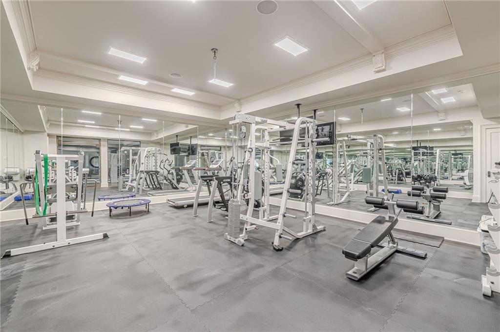 Indoor gym with weight machines and benches, mirrored walls, and gray flooring.