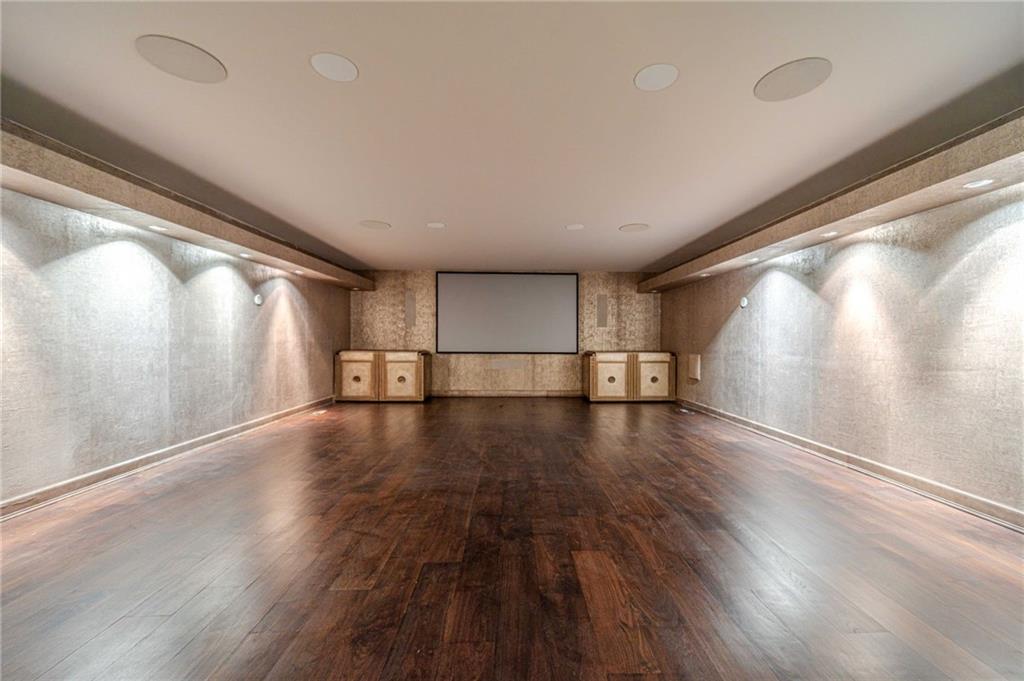 Empty home theater with hardwood floors, built-in cabinetry, and a projection screen.