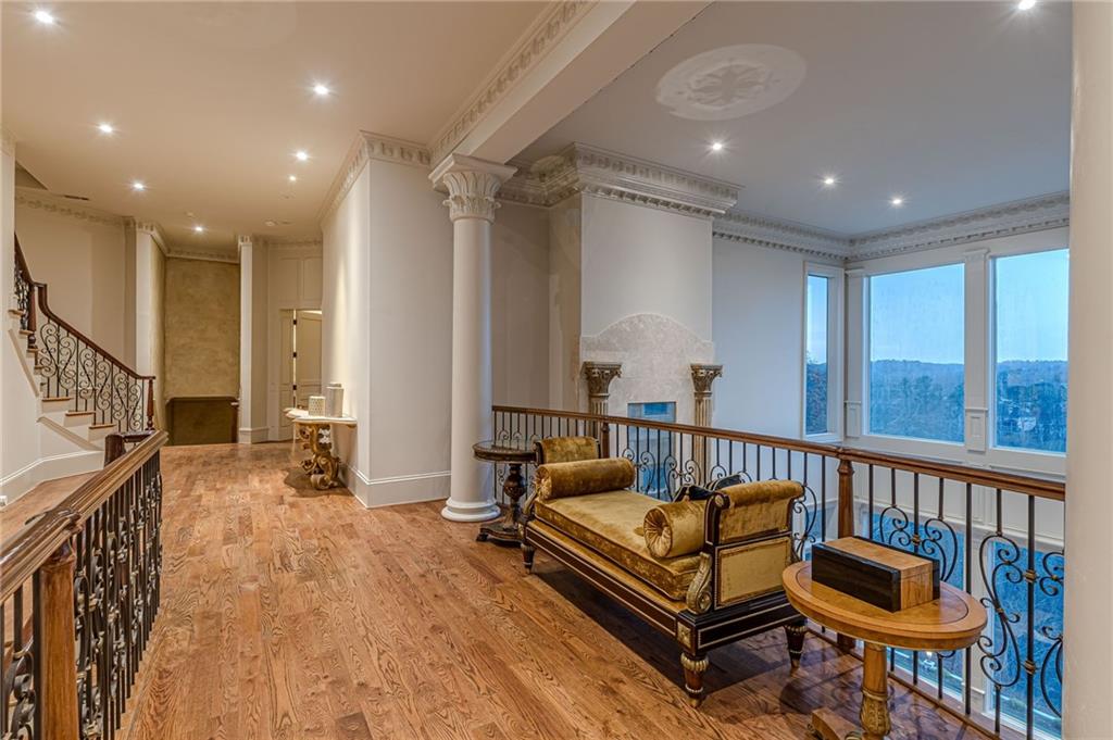 Sitting area with ornate columns, a carved fireplace, and large windows overlooking wooded hills.