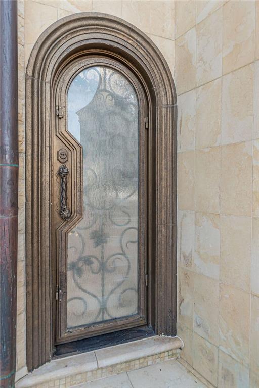 Arched entry door with decorative ironwork, framed by pale stone.