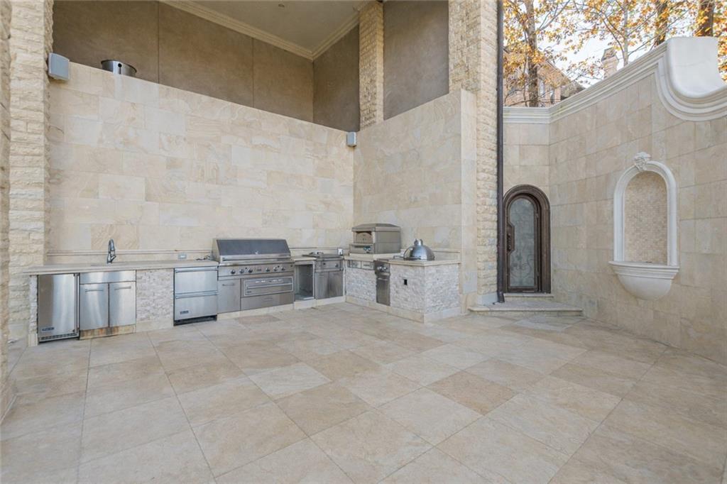 Stone courtyard outdoor kitchen with stainless steel appliances and a wall fountain.