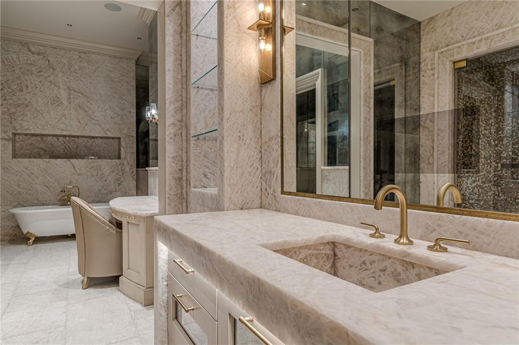 Marble bathroom with a large vanity, brass fixtures, soaking tub, and glass-enclosed shower.