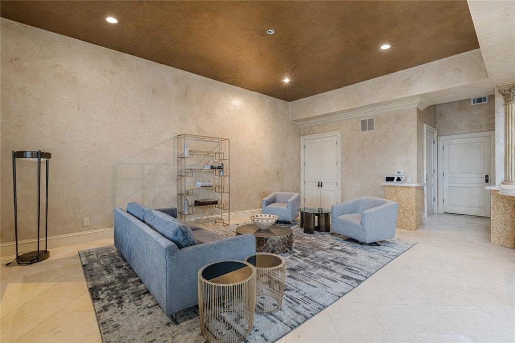 Living room with blue seating, a patterned rug, pale stone-look walls, and a warm wood ceiling.