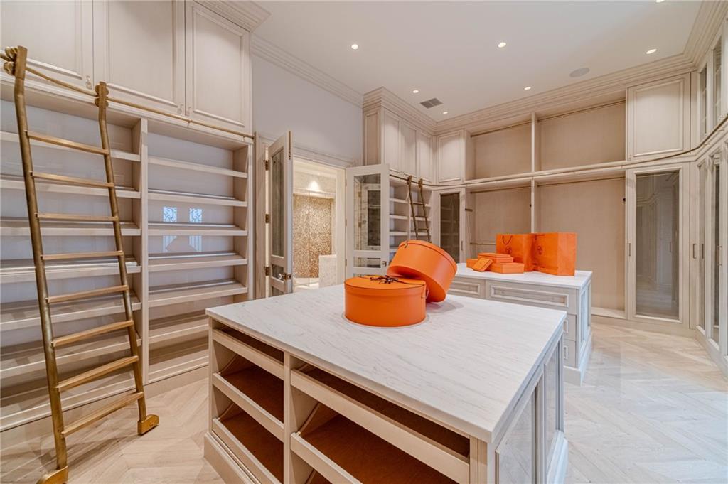 Walk-in closet with built-in shelving, rolling ladders, and central display islands.