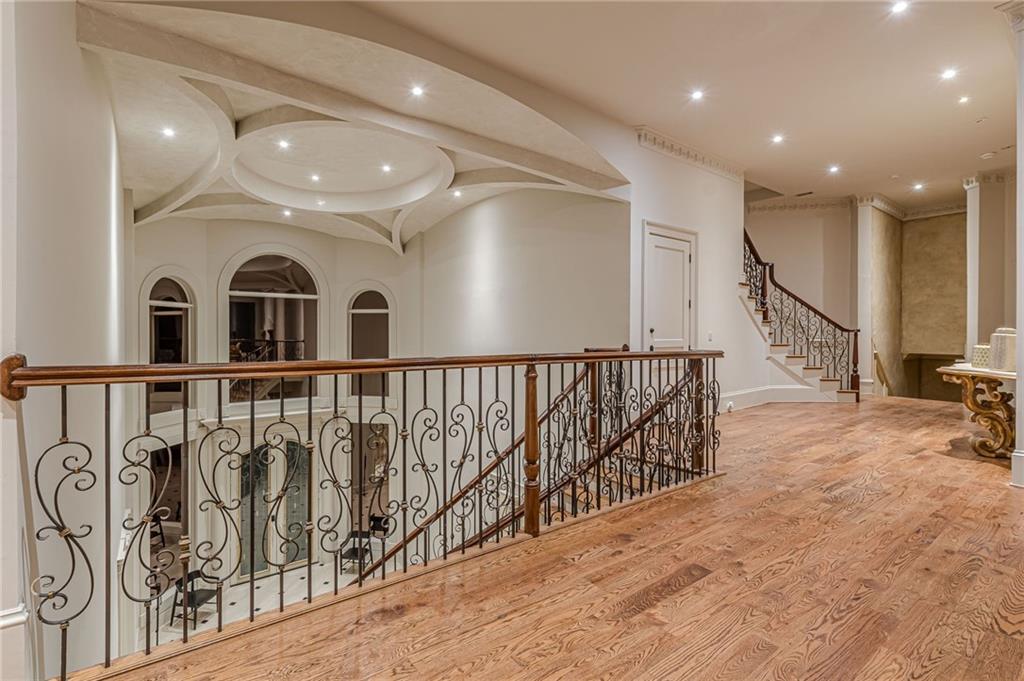 Hardwood upper landing with ornate iron railings and a sculptural ceiling.