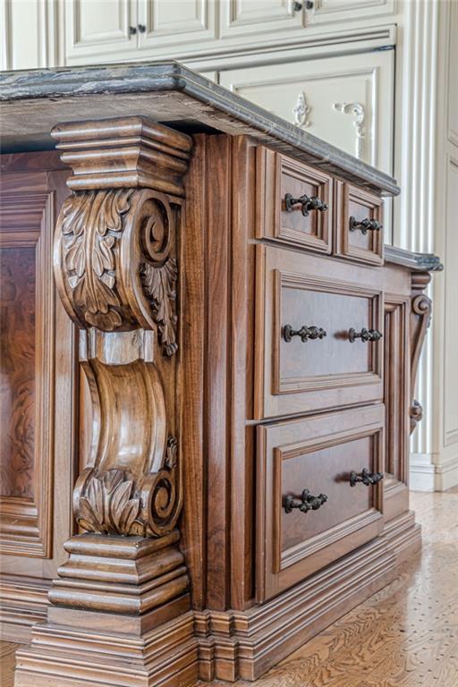 Ornate carved wood kitchen island with a dark stone countertop and antique-style drawer pulls.