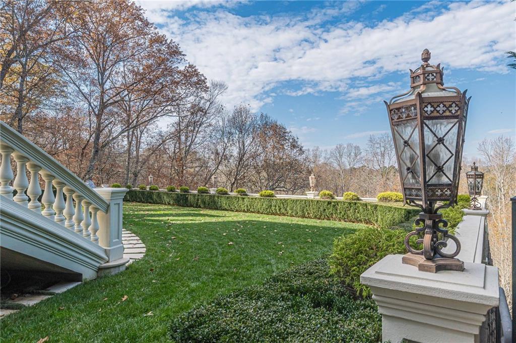Landscaped garden with a curved stone path, white balustrade, and ornate lanterns along the terrace.