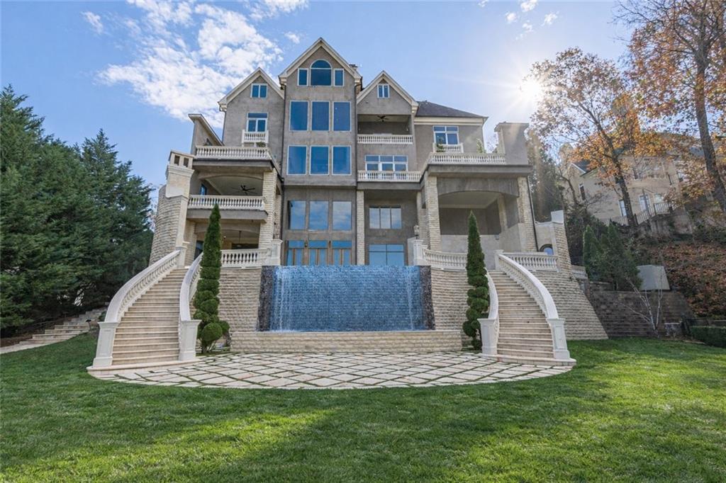 Large stone home with twin curved staircases and a central waterfall in the landscaped yard.