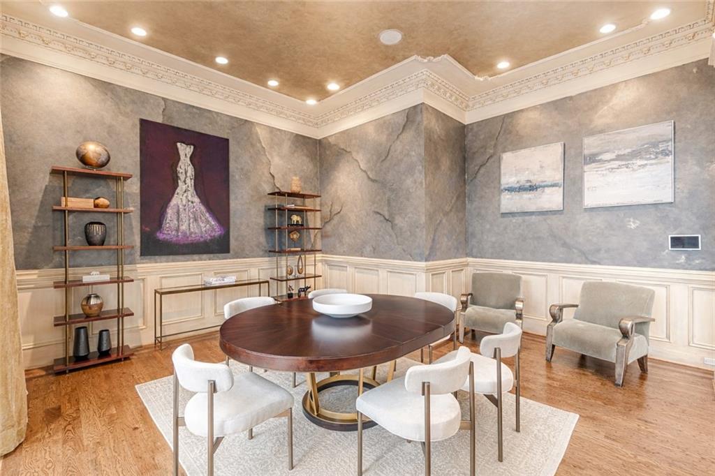 Formal dining room with a round table, white chairs, stone-textured walls, and ornate crown molding.