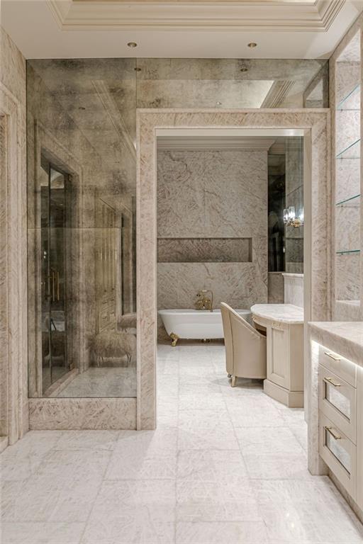 Marble bathroom with a freestanding tub, glass shower, and curved vanity.