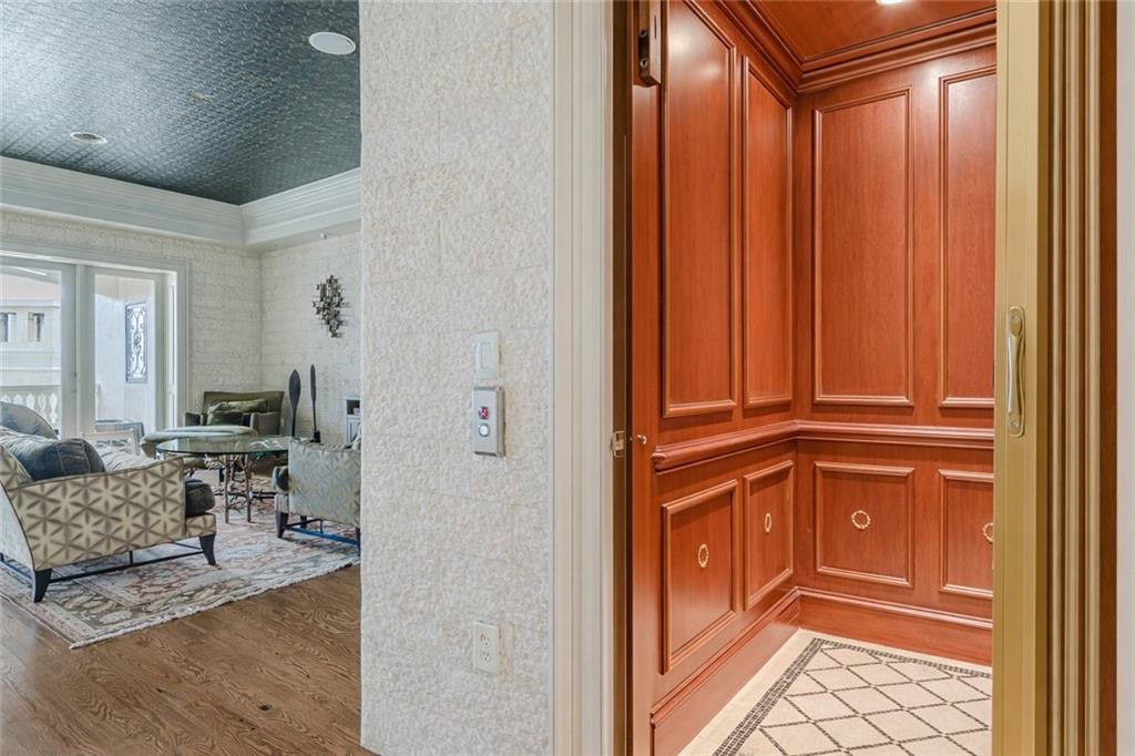 Wood-paneled residential elevator beside a furnished living room.