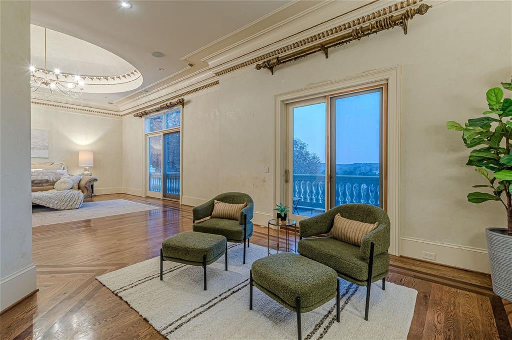 Furnished living room with green chairs, hardwood floors, and glass doors opening to a balcony.