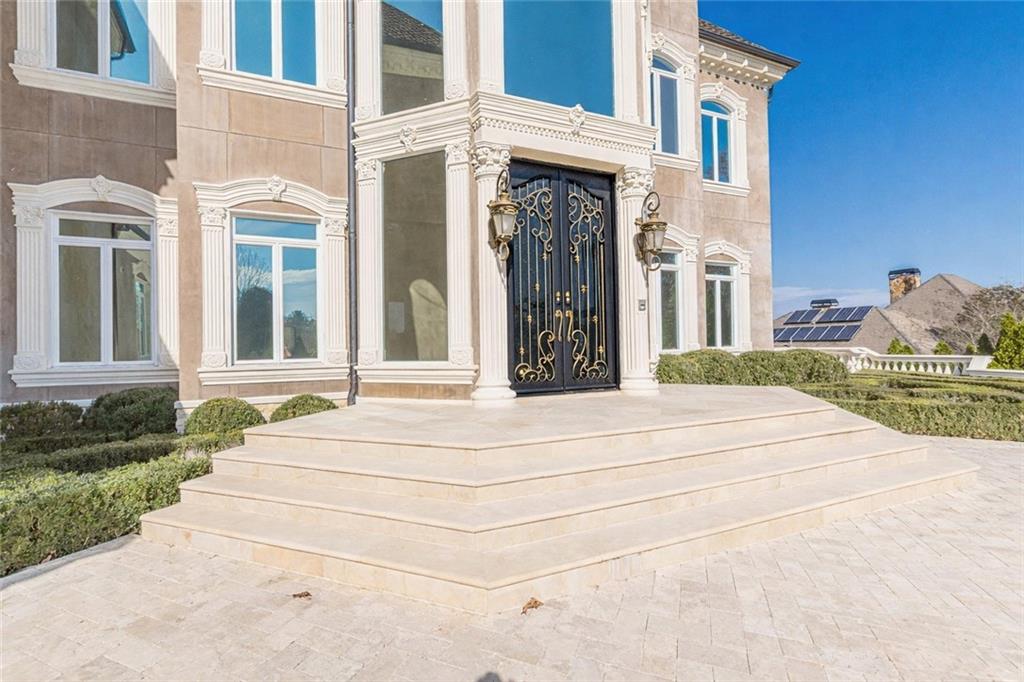 Ornate front entrance with black-and-gold double doors and broad stone steps.
