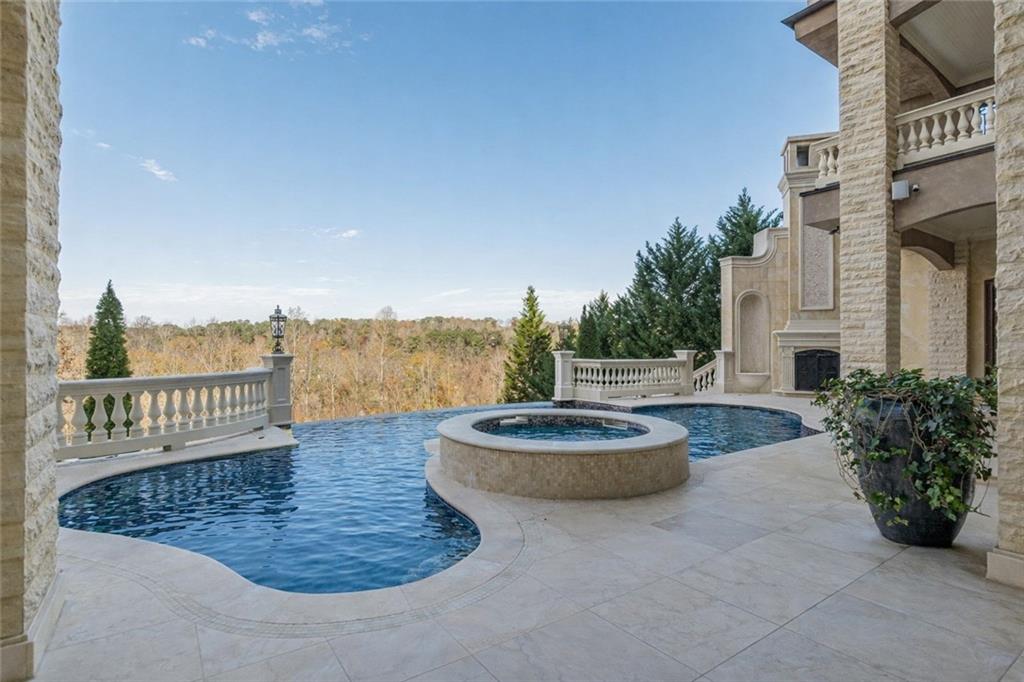 Pool terrace with a raised circular spa, stone paving, and wooded views.