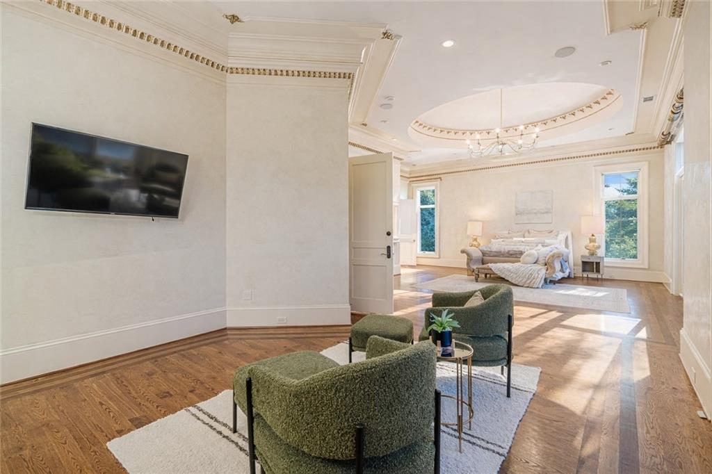 Formal living room with hardwood floors, ornate ceiling, chandelier, and seating area.