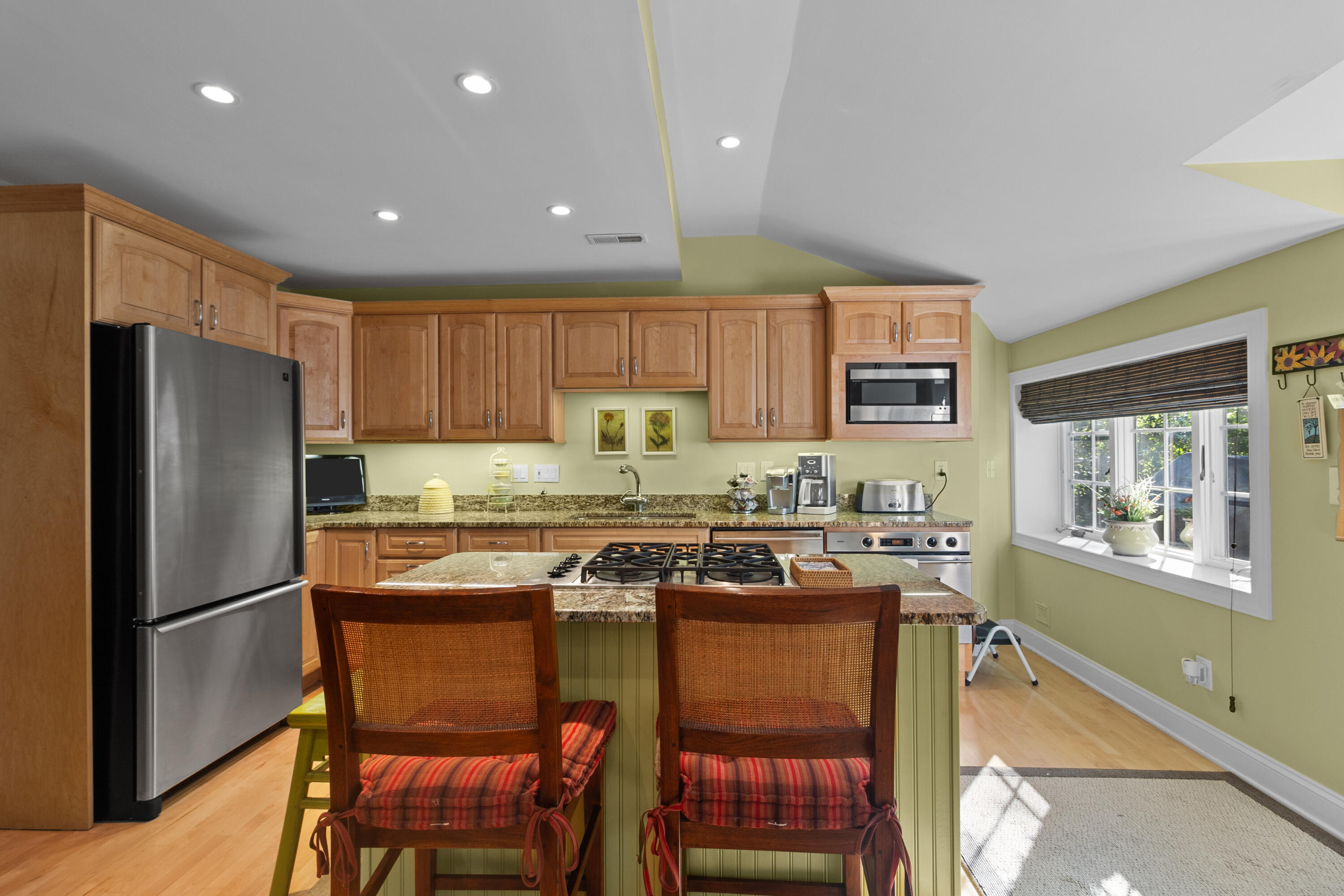 Kitchen with maple cabinets, granite counters, and a green island with a gas cooktop.