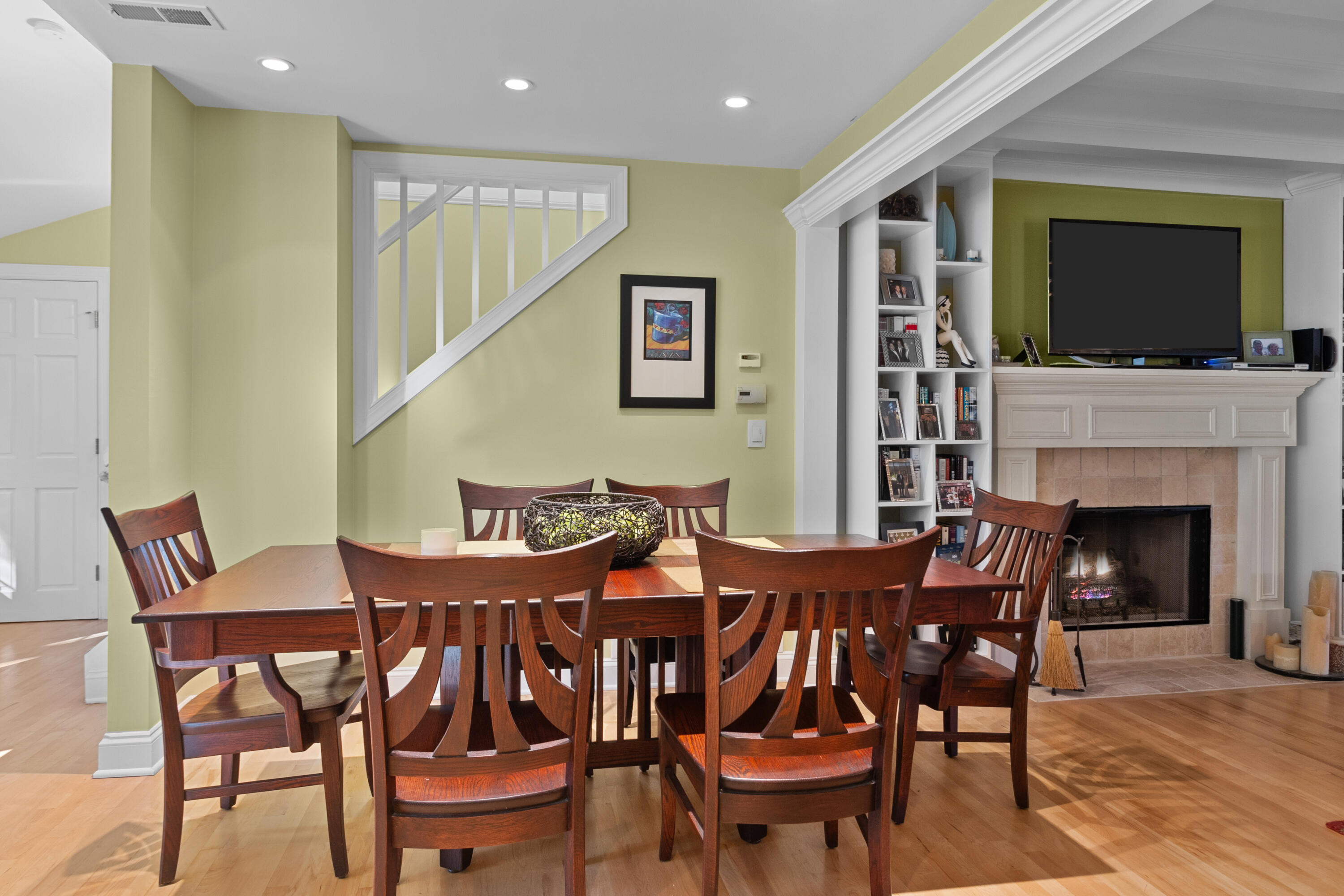 Dining room with a dark wood table beside a fireplace, built-in shelves, and a television.