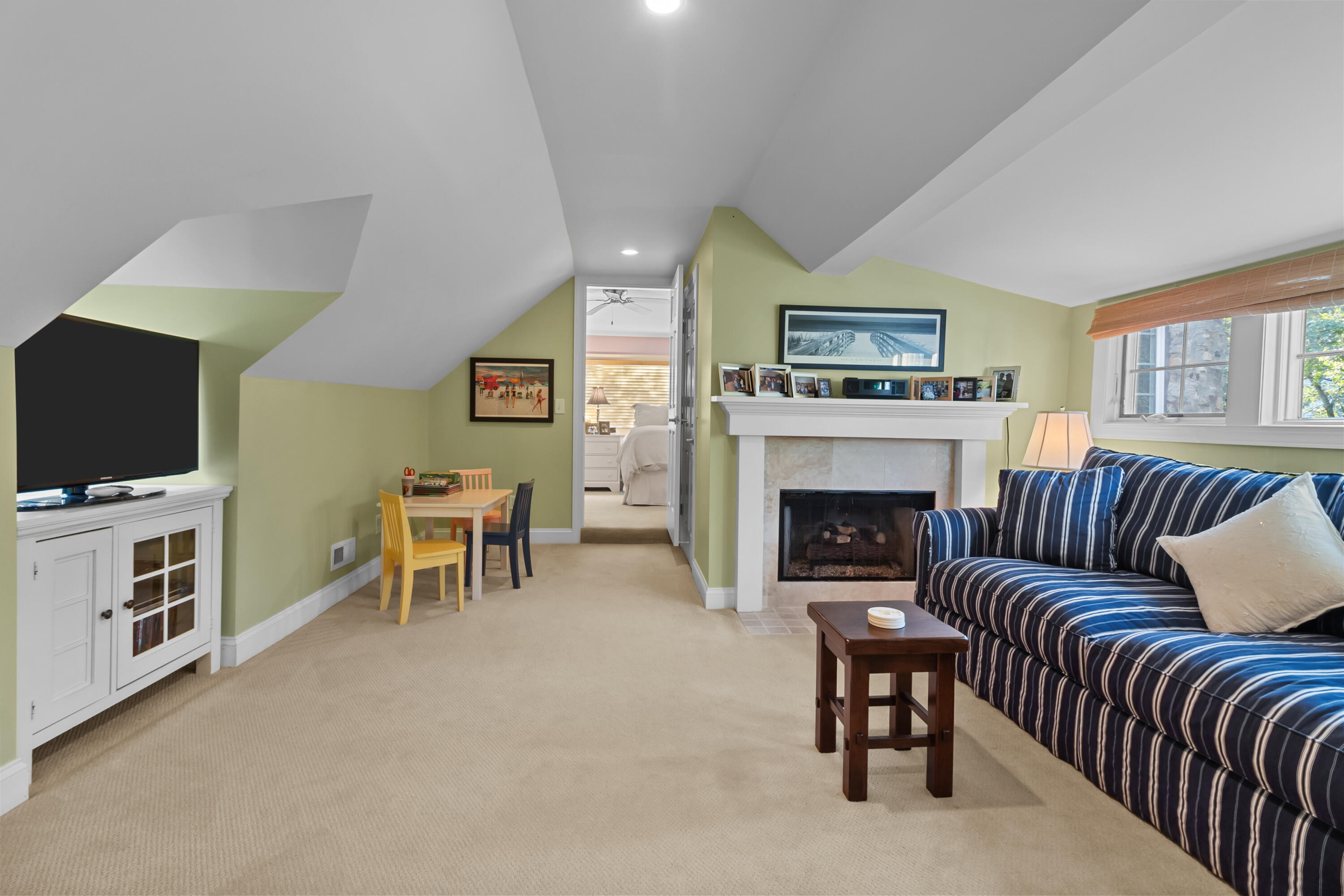 Furnished living room with a striped sofa, tiled fireplace, and vaulted ceiling.