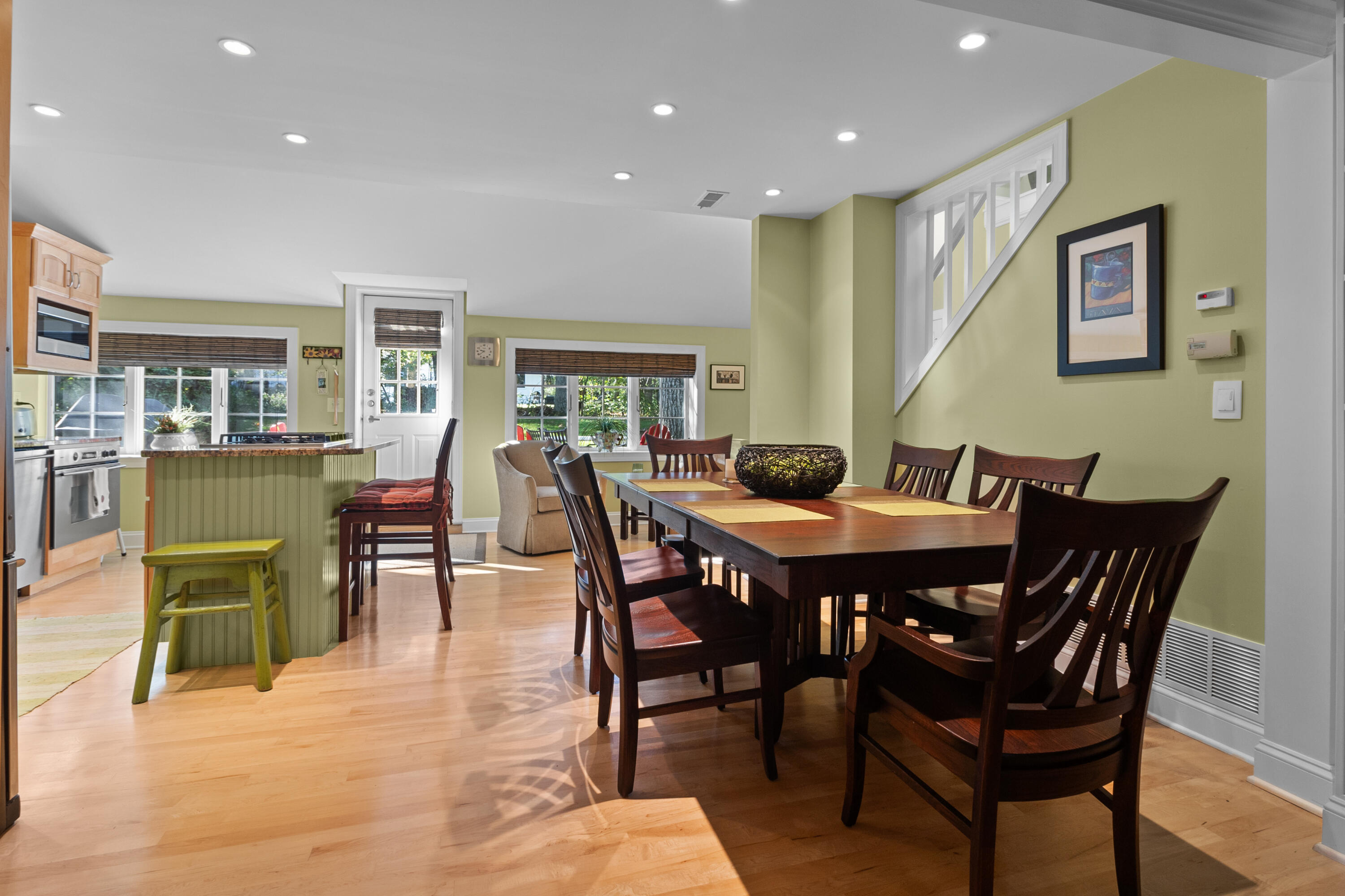 Dining room with a dark wood table beside an open kitchen and green breakfast bar.